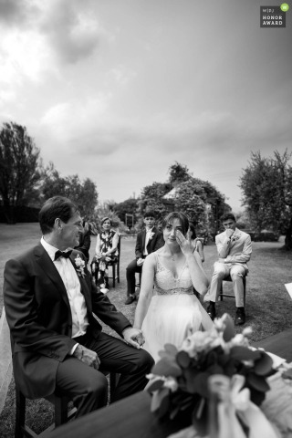 The bride tenderly wipes away a single tear during an emotional and heartfelt marriage ceremony held at the picturesque Macesina Country House in Bedizzole, within the Lombardy region of Italy.