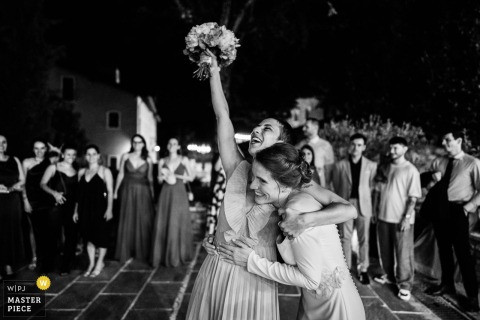 At Tenuta Borgo la Caccia in Pozzolengo, Italy, a bride hugs her friend who caught the bouquet. The award-winning photo highlights the photographer's skill at documenting the spontaneous, joyful emotions of a wedding day.