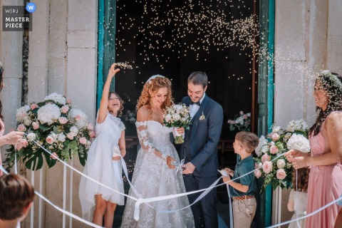 At Chiesa Santa Maria di Colonna in Trani, a bridesmaid throws something at close range as newlyweds exit the church. The award-winning photo highlights the photographer’s skill at documenting the spontaneous, joyful, and unique moments of a wedding.