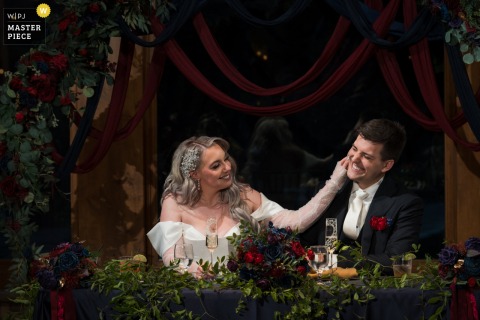 At Della Terra Mountain Chateau in Estes Park, Colorado, a bride lovingly watches her new husband as he is praised during wedding toasts. The award-winning photo highlights the photographer's skill at documenting genuine emotions.