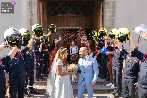 Newlyweds Walk Through Tunnel Of Firefighter Helmets In Châtel-Guyon France Amid Confetti And Bubbles In Châtel-Guyon, France, newlyweds walk through a tunnel of raised firefighter helmets. The award-winning photo highlights the photographer’s skill at documenting this joyful, unique tribute to brotherhood and celebration, surrounded by confetti and bubbl