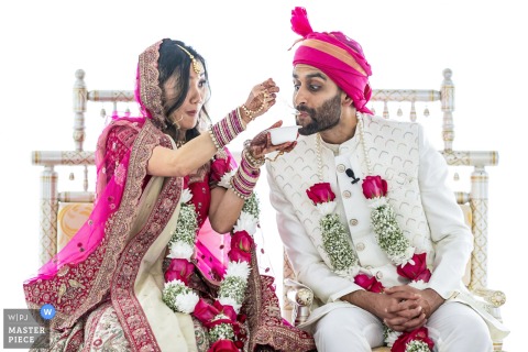 At Greystone at Piedmont Park in Atlanta, a bride feeds her groom sweets during a Kansar Bhakshan ritual. The award-winning photo documents this Hindu wedding tradition, symbolizing their first meal as a married couple.
