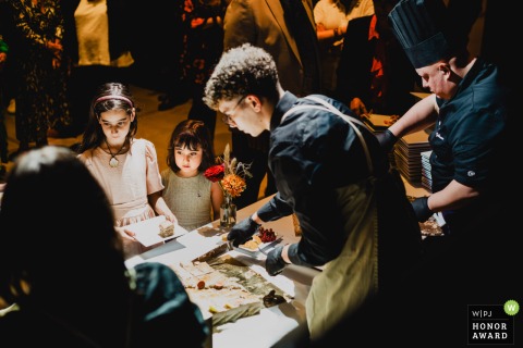 Two young girls wait with eager anticipation to be served by the caterer during the grand dessert presentation on the beautiful grounds of a wedding estate in Meuse, France.
