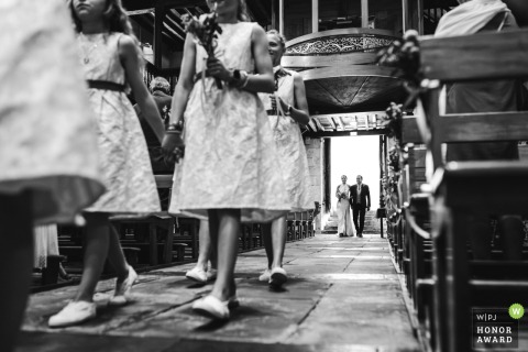 The bride makes her grand entrance into the Eglise d'Urrugne on her father's arm, led down the aisle by the wedding party's young flower girls and ring bearers.