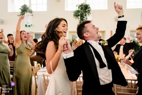 Newlyweds Make Joyful Dinner Entrance At Gloster House Ireland Highlighting Radiant Smiles And Celebration At Gloster House in Ireland, the photographer captures the joyful entrance of the newlyweds for dinner, expertly highlighting radiant smiles and the celebratory energy of their shared moment.