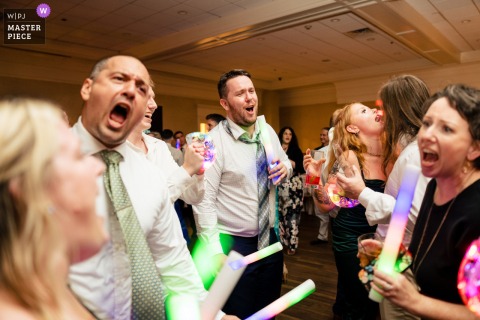 At a Philadelphia reception, the photographer captures wedding guests belting out a favorite tune, mouths wide open and hearts fully engaged, expertly freezing the exuberant unity and joy of the celebration.