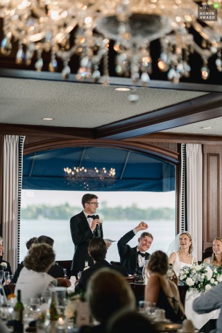 During a spirited best man’s speech at the Oconomowoc Lake Club in Wisconsin, the groom raises his fist in a triumphant gesture of celebration and agreement from the table.