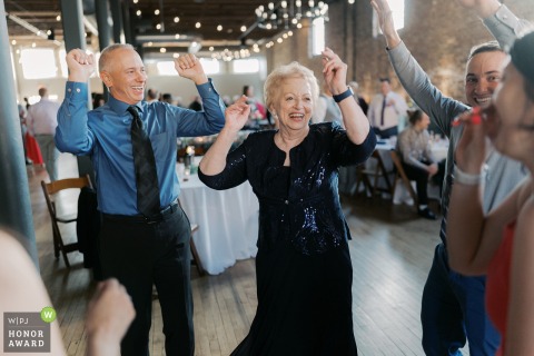 A lively grandmother, affectionately dubbed the party grandma, dances with incredible energy and spirit during the wedding reception held at the historic Mercantile Hall in Burlington, Wisconsin.