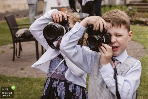 Young aspiring photographers use professional cameras to document the drinks reception at Hazlewood Castle in West Yorkshire, capturing the celebration from a unique, youthful perspective during the festivities.