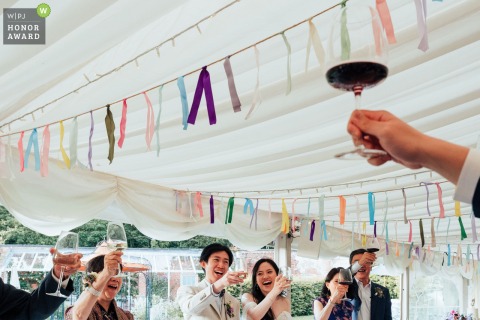 A speaker delivers a heartfelt toast from the top table, raising a glass to the newlyweds during a joyful wedding breakfast at The Walled Garden in Nottingham, UK.