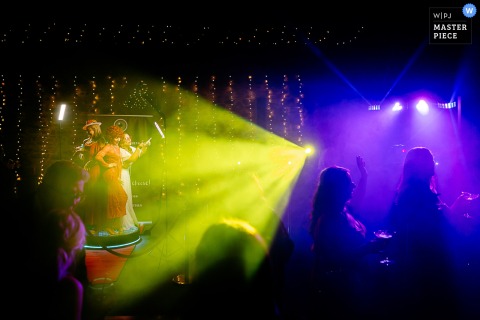 At New House Farm, the photographer captures party time with guests illuminated by vibrant yellow and purple DJ lights, showcasing dynamic atmosphere and skilled use of color-driven celebration moments.