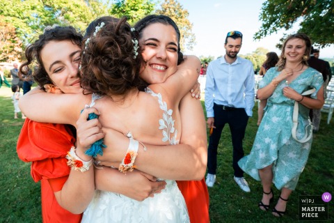 French Château Bride's Joyful Hug with Friends Captures Heartfelt Celebration At Château du Prada in Saint-Lon-les-Mines, France, the photographer captures the bride hugging her friends, expertly freezing a joyful, affectionate moment that radiates friendship and heartfelt celebration.