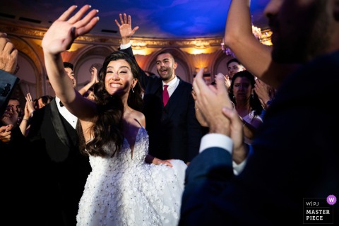 Bride on dance floor enthusiastically waves to a friend at the Fairmont Copley Plaza, Boston, MA.