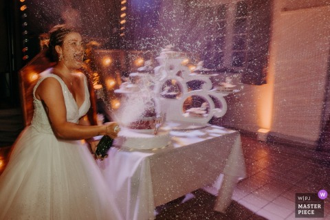 At Salle des Fêtes, the photographer captures a lively champagne shower as the bride sprays guests at the cake cutting, expertly freezing celebration, joyful energy, and playful spontaneity in a single frame.