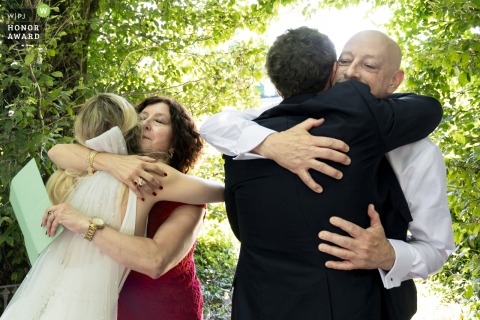 Deeply emotional double hugs are shared between the bride and her parents following a touching speech during the wedding ceremony held at the elegant Château de Montplaisant in Montagnat.