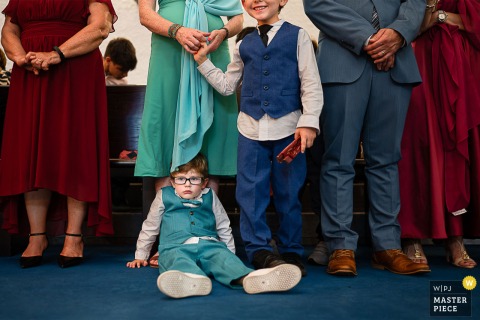 At a ceremony in Cagliari, Sardinia, the photographer captures a bored child sitting on the ground at the feet of standing guests, expertly conveying candid humor and the honest moments that color wedding days.