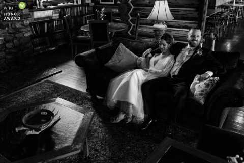 The bride and groom share a quiet, relaxing moment together on a couch in the lobby of the Double Arrow Lodge in Seeley, Montana, before their wedding ceremony begins.
