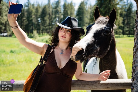 In Ronan, Montana, the photographer captures a playful moment as a female guest in a cowboy hat takes a horse selfie, highlighting charm, character, and a keen eye for unique celebration details.