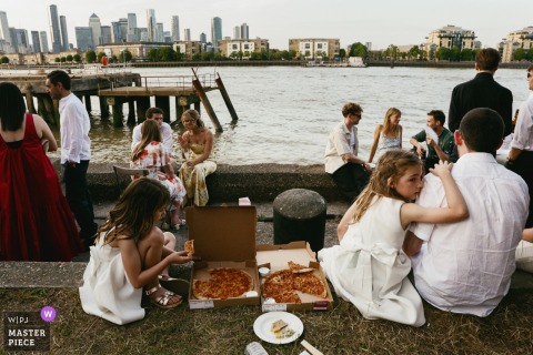 London's Master Shipwright's House: Guests sit by river at dusk, eating pizza.