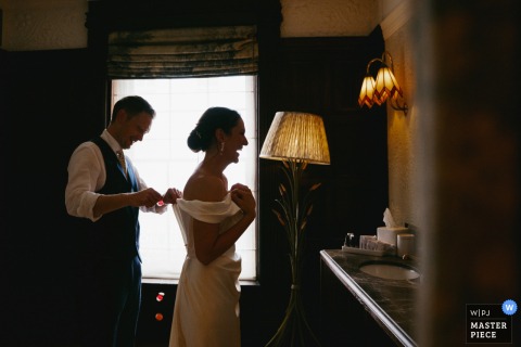 Kettner's Townhouse, London: The groom helps the bride remove confetti from her dress.