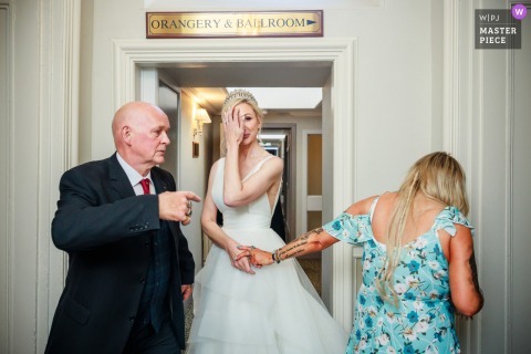 At Balbirnie House Hotel in Glenrothes, the photographer captures emotional guests warmly greeting the bride in a doorway, expertly preserving heartfelt reactions and genuine connection in an intimate indoor moment.