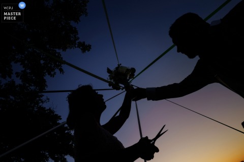Sunset silhouettes: bride and groom play the bouquet and ribbons game at Château Caillivet, France.