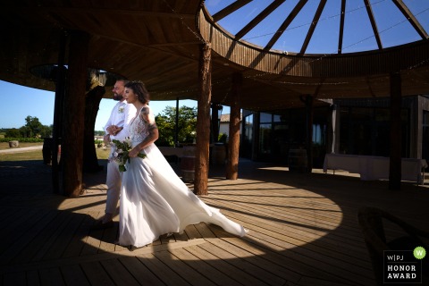 Accompanied by her brother, the bride walks toward her non-religious wedding ceremony amidst the scenic vineyards and historic architecture of Château Caillivet in the Gironde region of France.