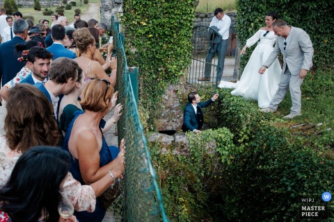 At Abbaye du Val des Choues, the photographer captures a unique moment as the bride and groom, aided by a soaked witness, release a salamander found at the cocktail party, showcasing storytelling and natural spontaneity.