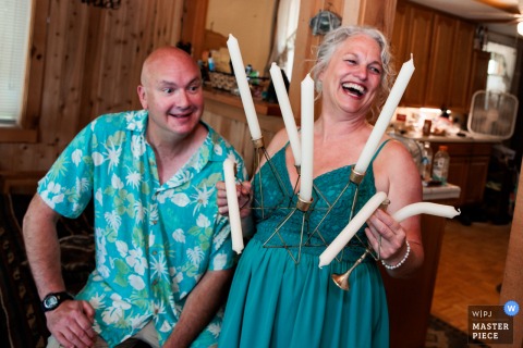 Duluth Mother's Joyful Laugh with Melting Candles Wedding Celebration In Duluth, Minnesota, the photographer captures a joyful moment as the mother laughs while holding melting, bent candles in a holder, skillfully highlighting candid humor and genuine celebration.