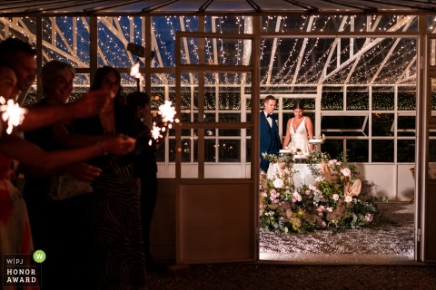 The bride and groom arrive for their cake cutting ceremony at Baronesse Tacco in San Floriano del Collio, Italy, greeted by guests holding glowing sparklers outside the elegant gazebo.