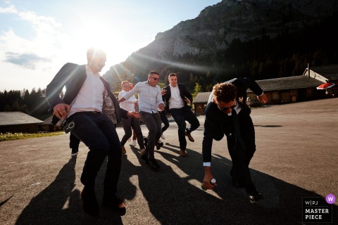 Switzerland: Groomsmen Dash for a Bottle in Golden Light At a Fribourg, Switzerland reception, the photographer expertly captures single men racing for a bottle outside, dramatically backlit by low, beaming sun, highlighting energy, timing, and striking visual storytelling.