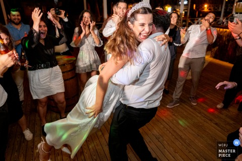 At Goga Beach Club in Kilyos, Istanbul, the photographer captures a joyful, lively scene as the groom swings his laughing bride on the dance floor, perfectly freezing a moment of pure happiness and fun.