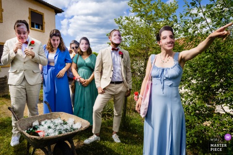 At Chateau Dupeuble, Beaujolais, the wedding party readies beers in a wheelbarrow while wearing photo masks of the bride and groom. The photographer’s creative eye captures humor and playful spirit in this lively moment.