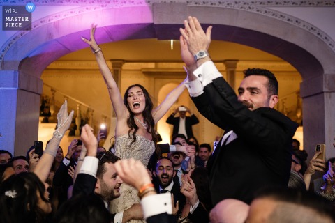 At a Lisbon reception, the bride and groom ride above everyone’s heads as they open the dance floor. The photographer’s technical mastery captures this epic, exhilarating start to the celebration.
