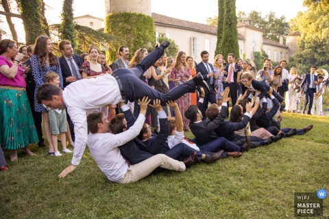 At Chateau de Malliac, Condom, France, guests crowd-surf on the grass during a lively “paquebot.” The photographer’s skill captures the energy and exuberance of this unique overhead celebration.