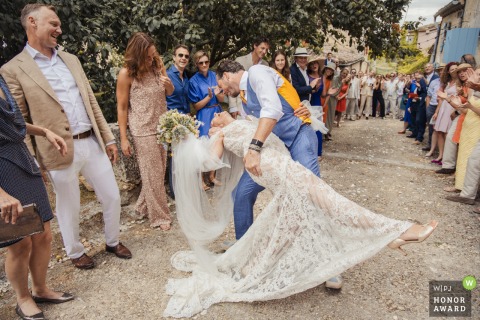 Groom Leans In To Share A Romantic Kiss Amidst Festive Confetti At The Castelnau In France Following a colorful confetti celebration at The Castelnau in Lectoure, France, the groom leans in to share a romantic kiss with his new bride amidst the lingering festive atmosphere.