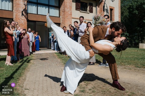 Outside Plaisance du Touch city hall, the bride and groom dip and kiss in the sun, watched by guests. The photographer’s timing beautifully captures the romance and exuberance of this joyful exit.