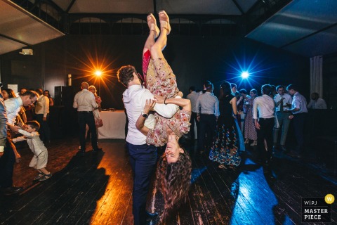 At Domaine de Montchevreuil, guests dance energetically to rock music as a man spins his partner upside down. The photographer’s technical expertise captures the excitement and motion of the lively wedding celebration.