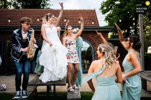 At Froginwell Vineyard, a saxophonist dances on a table with the bridal party. The photographer’s creative timing captures the exuberant, music-filled celebration and lively energy of the women at the wedding.