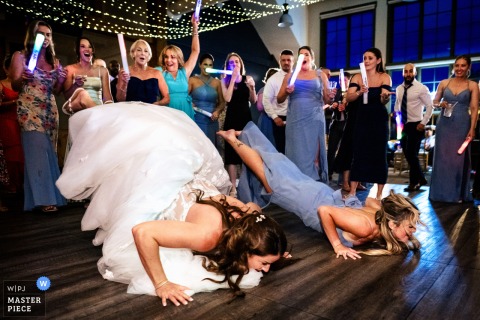 At Sugarbush Resort, the bride and her maid of honor do the worm during the reception. The photographer’s quick timing and technical expertise capture the celebratory energy and fun of the moment.
