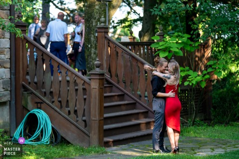 At Springwood Manor, a couple privately enjoys a quiet moment in the shaded lawn during cocktail hour. The photographer’s creative perspective captures intimacy amid the lively celebration above.
