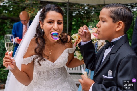 At Kasteel van Rhoon in the Netherlands, the bride shares bubble fun with one of the children during the wedding ceremony, adding joy and laughter to the occasion.