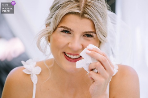At Schlosshotel Gimborn in Marienheide, Germany, the bride becomes emotional during the ceremony, wiping her face with a kerchief in a close, intimate shot.