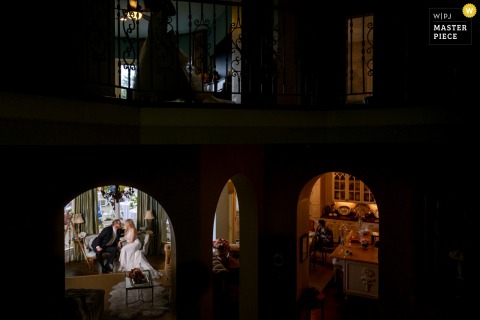At the Chateau in Kalama, Washington, the bride and groom share a quiet moment together in an ornate home, captured from a staircase above before their grand reception entrance downstairs.