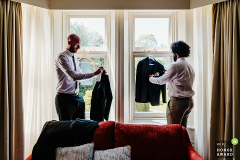 The Marriot Delta Hotel in Preston, UK, sets the scene for a quiet moment where the groom and his groomsman prepare together in soft natural light by a window.