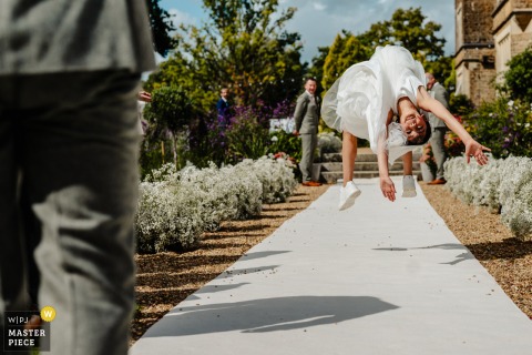 At Hartsfield Manor in Surrey, UK, a flower girl performs a backflip down the aisle, delighting guests with her playful energy during the wedding ceremony.