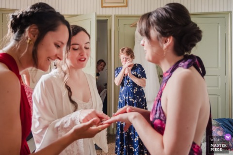 At the wedding venue in Saint-Brieuc, Côtes-d'Armor, Brittany, France, under the mother’s watchful eye, a make-up artist observes the bride and her sister, displaying a pretty ring on her finger.