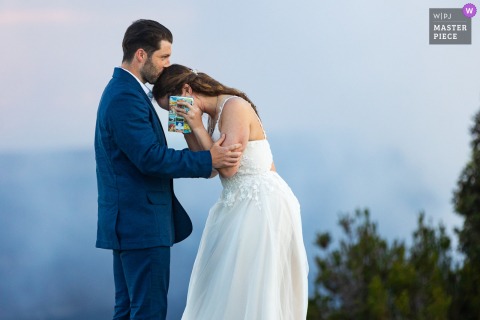 At Kilauea Crater Rim in Hawaii Volcanoes National Park, the couple comforts each other during their emotional ceremony, set against a minimalist, soft blue sky and sweeping volcanic views.