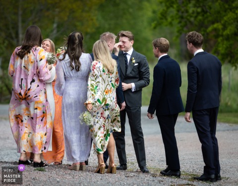 At Nybynäs Gård in Västerås, Sweden, newlyweds celebrate with friends after the ceremony, sharing laughter and joy during the wedding festivities.