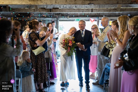 At Smedjans Hus in Barsebäckshamn, Sweden, the bride walks down the aisle arm-in-arm with her father during the wedding ceremony. Her head is on his shoulder.